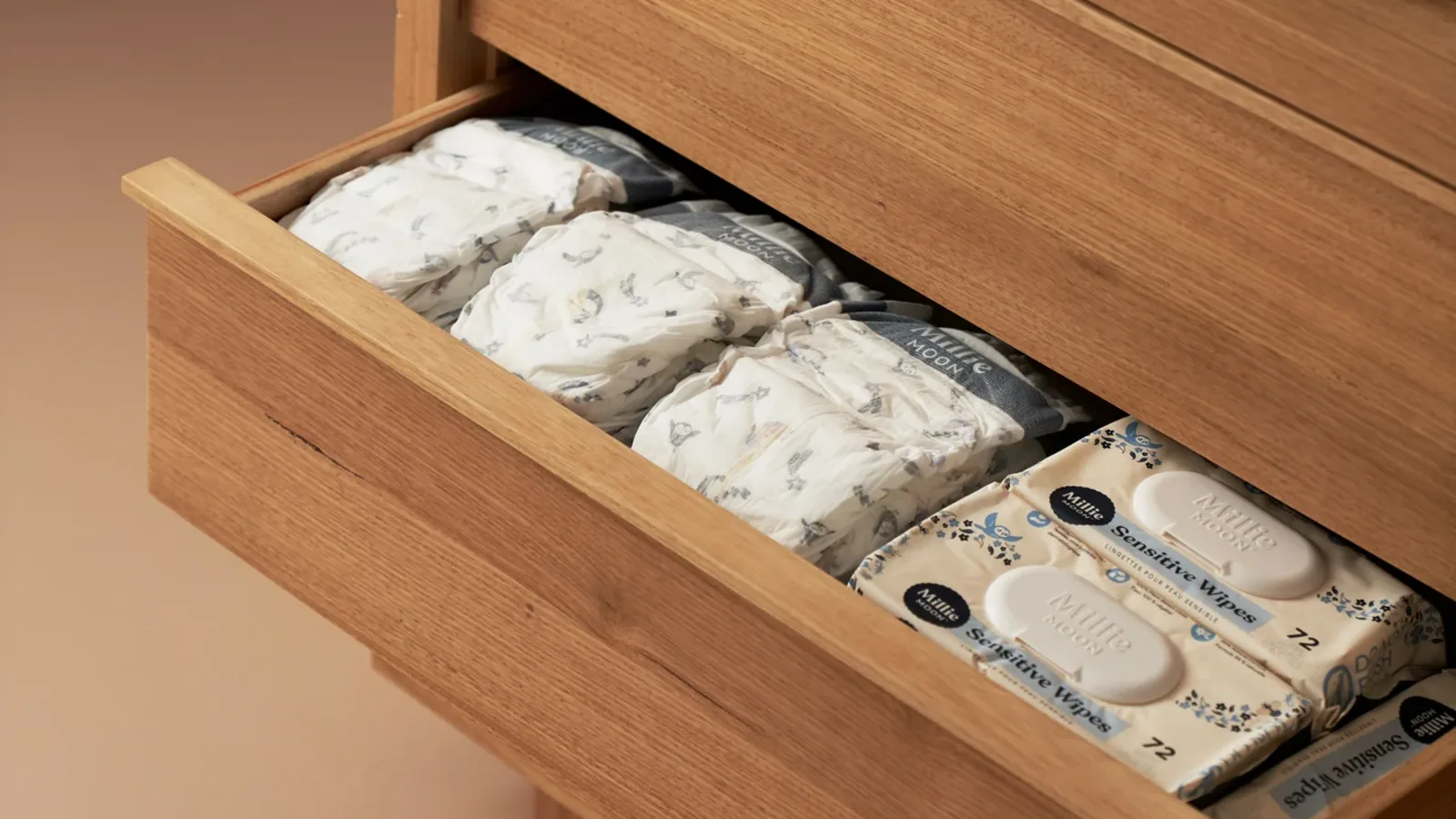 An open drawer of folded nappies and packs of wipes