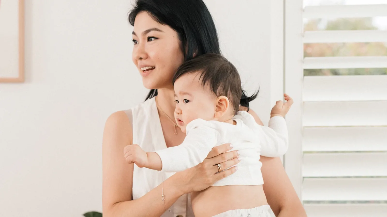 A parent holding a baby in a nappy against one hip