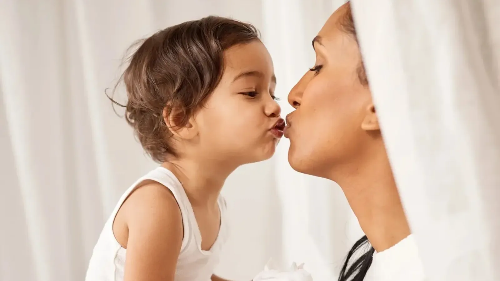 A parent and toddler sharing a kiss