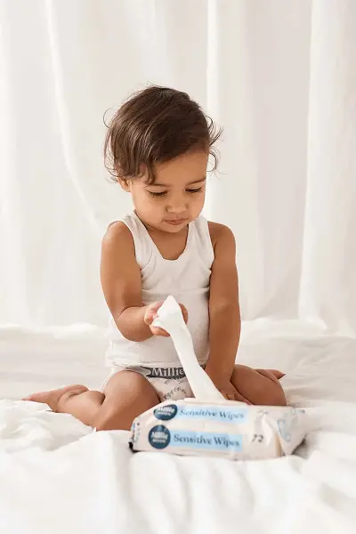 Toddler in a Millie Moon diaper pulling a wipe from a pack of Millie Moon Sensitive Wipes