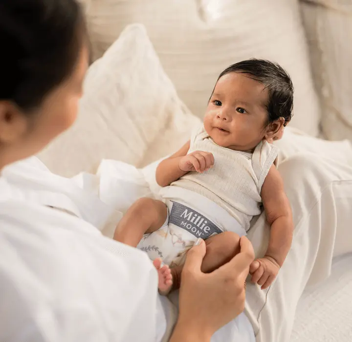 Parent cradling a newborn wearing a Millie Moon Luxury Diaper