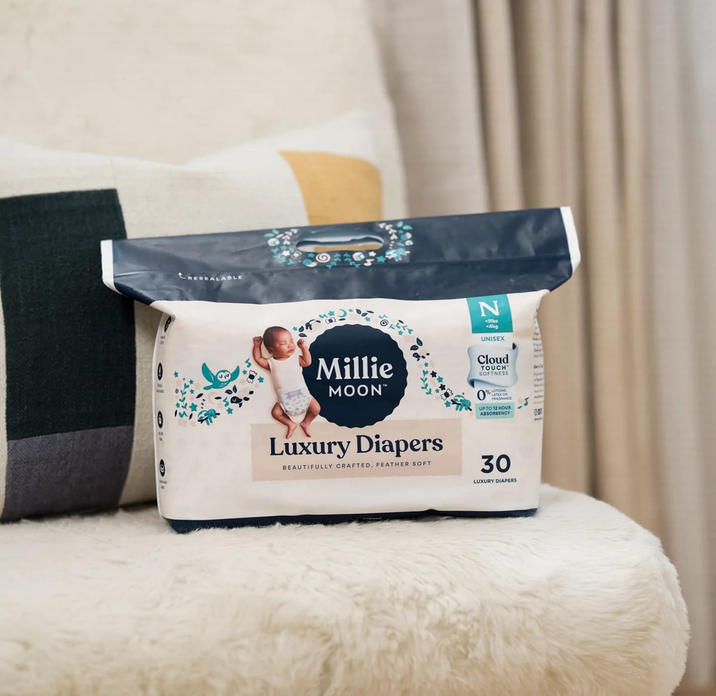 Pack of Millie Moon Luxury Diapers in newborn size resting on a soft armchair