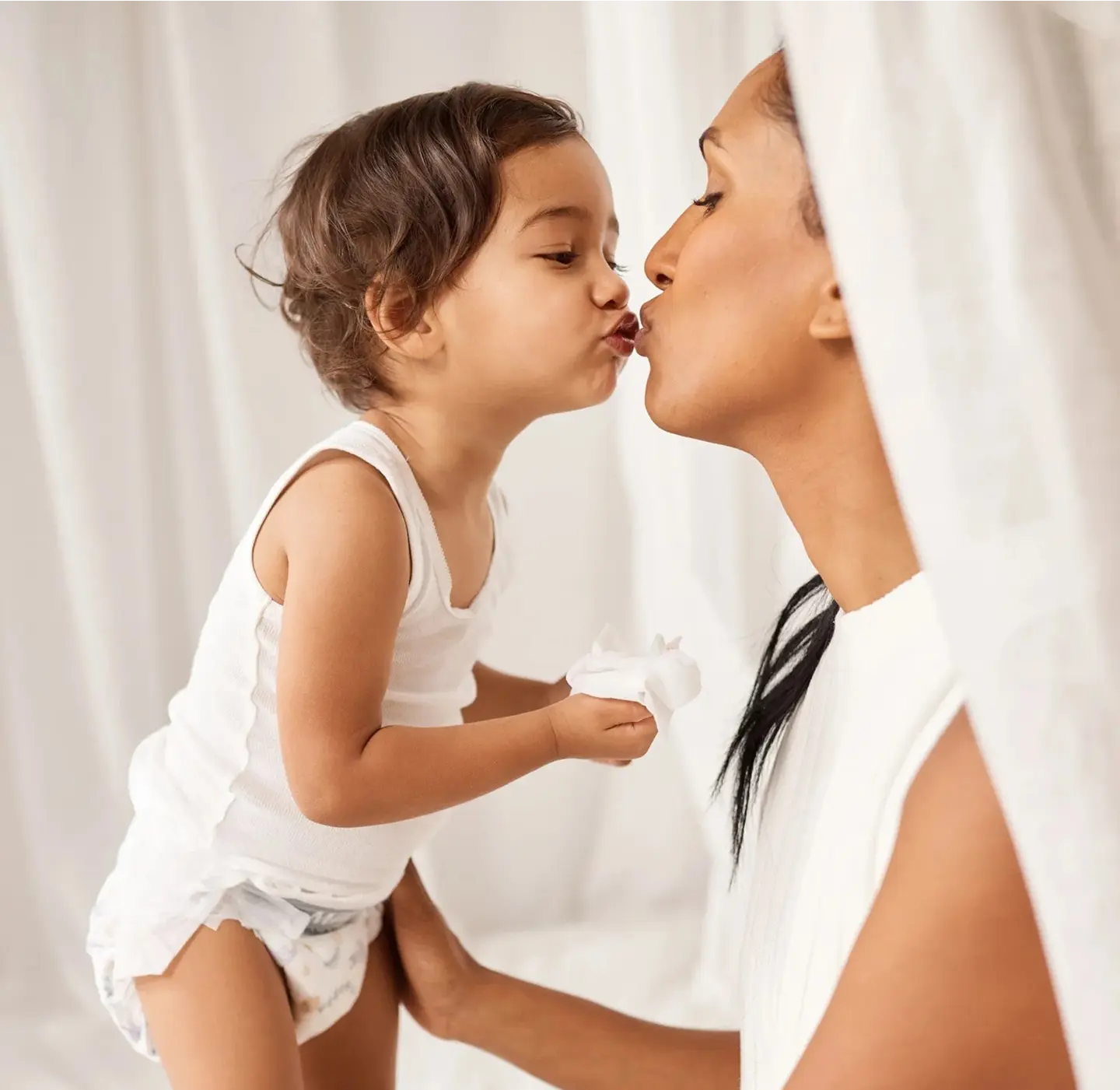 Parent lifting a toddler wearing a Millie Moon diaper for a kiss